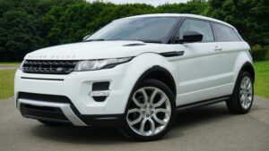 Used car Range Rover parked on a road in a green outdoor setting, showcasing its luxury design.