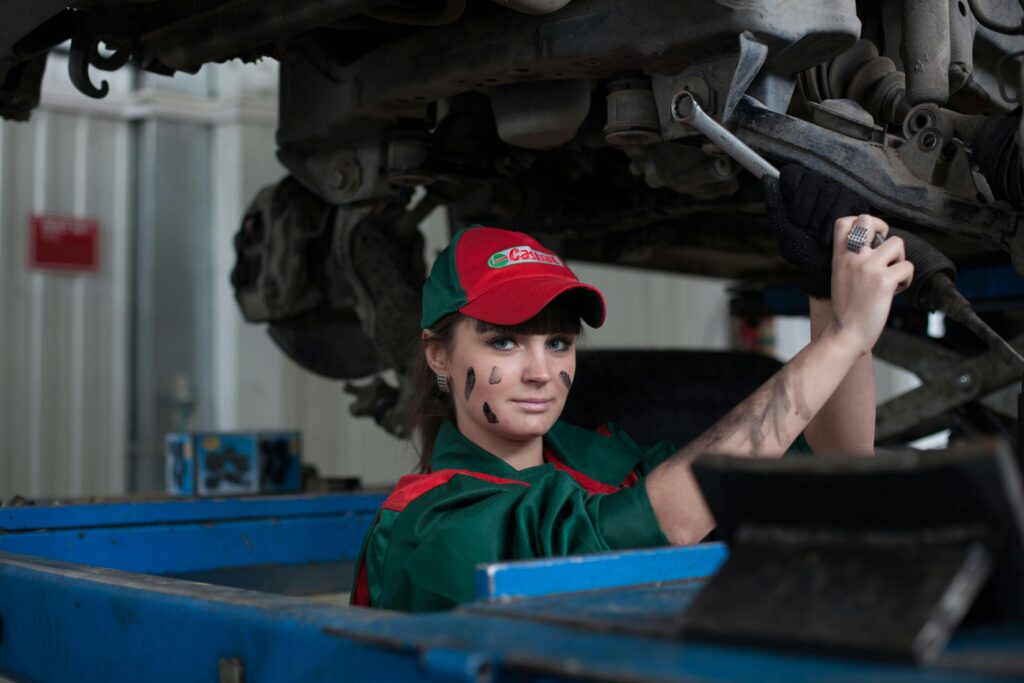 Female mechanic maintaining a car in an auto repair shop, showcasing Car Maintenance