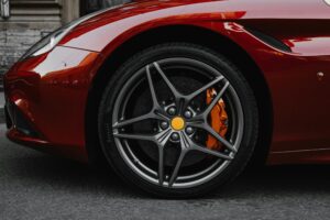 High-quality image of a red luxury car's wheel, highlighting its shiny alloy rims and brake system.